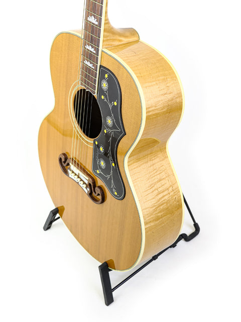 2001 Gibson SJ-200 guitar resting on a stand, set against a bright white backdrop.