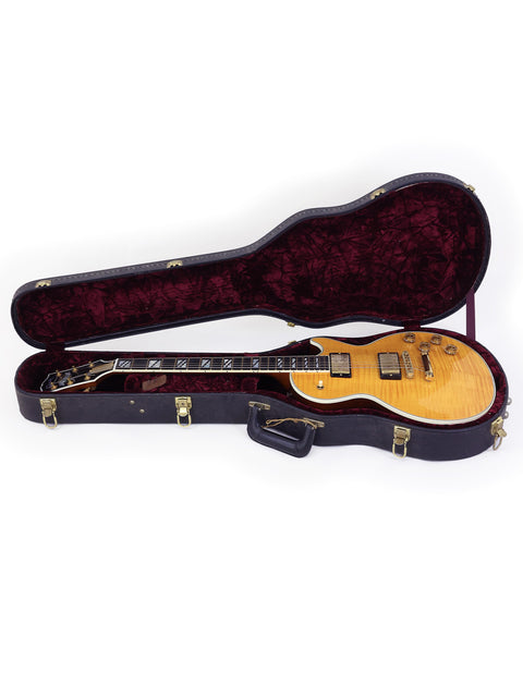 2003 Gibson Les Paul Supreme guitar nestled in a case, set on a pristine white background, highlighting its craftsmanship.