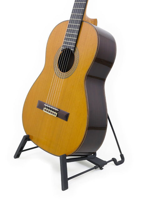 2021 Francisco Esteve 9C/B classical guitar is positioned on a stand, set against a pristine white background.