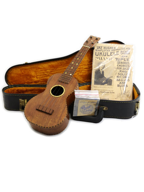  A 1924 Weissenborn Miami Style 3 Koa ukulele in its case, accompanied by a guitar, celebrating vintage musical instruments.