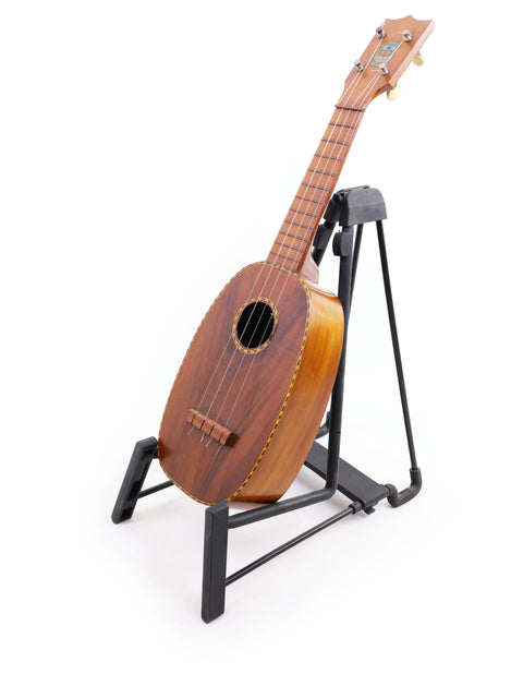 A 1928 Kamaka Pineapple Style #3 ukulele on a stand, highlighting its elegant wooden body and classic design.
