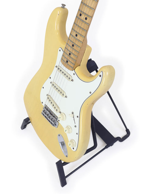 A 1954 USA Fender Stratocaster electric guitar in yellow, prominently positioned on a stand for display.
