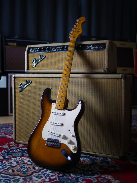 A 1954 USA Fender Stratocaster guitar with an amp, artistically arranged on a patterned rug.