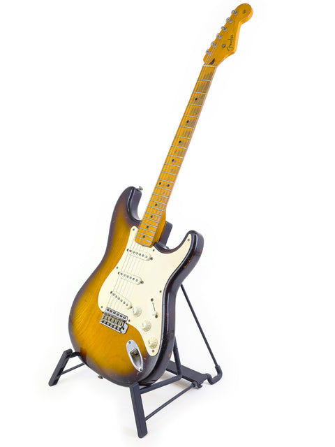 A 1954 Vintage Fender Stratocaster guitar displayed on a stand, set against a pristine white background for emphasis.