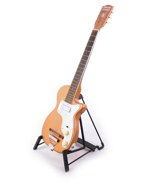 A 1955 Harmony H44 Stratotone guitar elegantly positioned on a stand with a bright white background.
