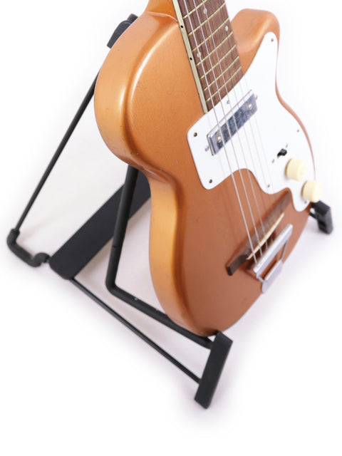 A 1955 Harmony H44 Stratotone guitar on a stand, showcased with a simple white background for emphasis.