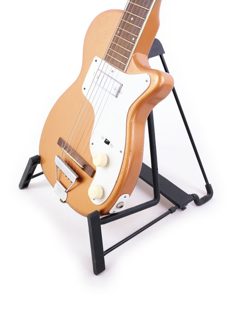A 1955 Harmony H44 Stratotone guitar showcased on a stand, set against a bright white background.