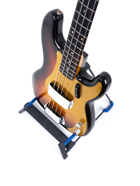 A 1958/59 vintage Fender Precision Bass guitar displayed on a stand, adorned with a blue strap.
