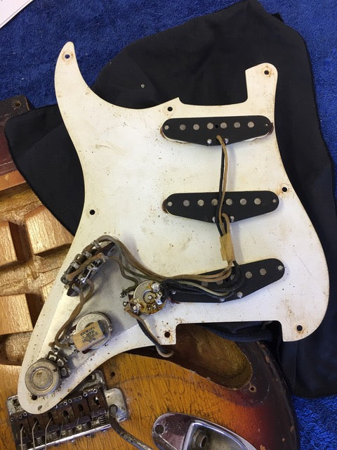 A 1958 Fender Stratocaster with a broken neck and bridge, reflecting its storied past and vintage character.
