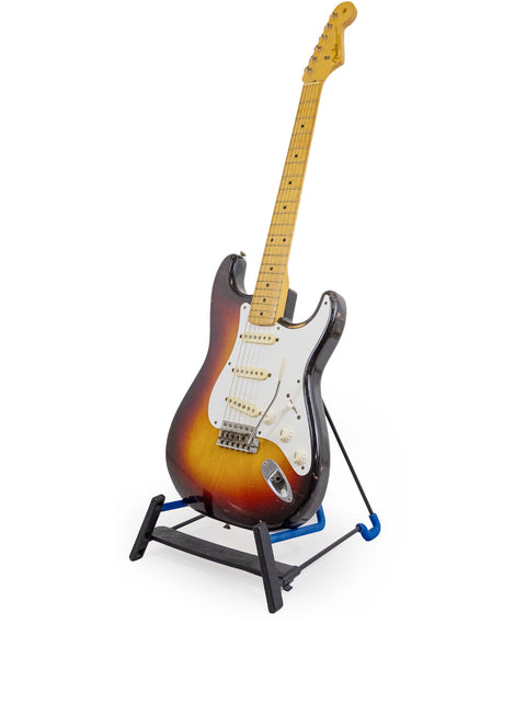 A 1958 Vintage Fender Stratocaster displayed on a stand with a white backdrop.
