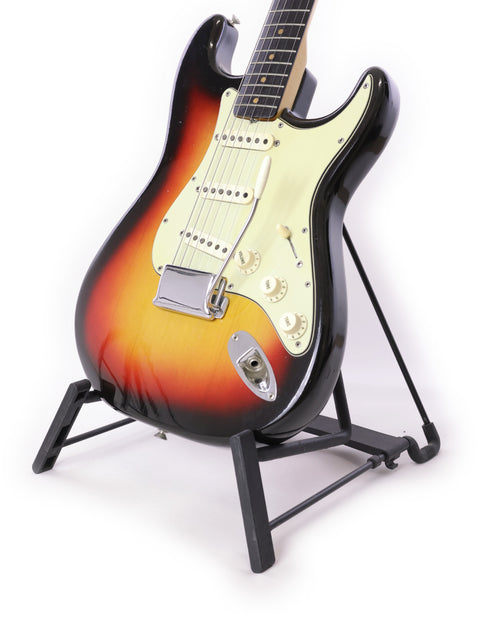 A 1964 Fender L Series Stratocaster in striking Fiesta Red displayed on a stand, featuring a plain white background.
