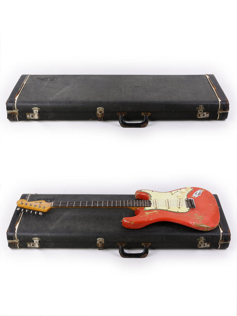 A 1964 vintage Fender Stratocaster in striking Fiesta Red, accompanied by a sleek black case, highlighting its iconic style.

