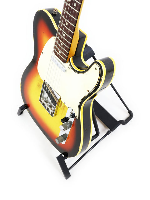 A 1966 Fender Custom Telecaster in vibrant yellow and orange, elegantly positioned on a stand for display.