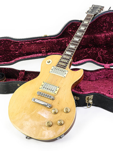 A 1973 Gibson Les Paul Deluxe guitar in a case, featuring a striking yellow color and vintage appeal.