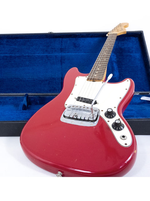 A 1976 Fender Bronco electric guitar in a case, featuring a vibrant red finish and vintage appeal.