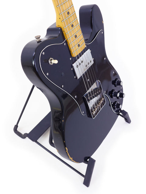 A 1978 black Fender Telecaster Custom electric guitar elegantly positioned on a stand, highlighting its iconic features.