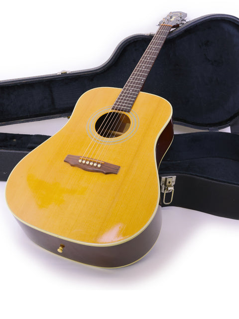  A 1989 Guild D40 guitar lies in its case on a white background, emphasizing its elegant shape and timeless appeal.