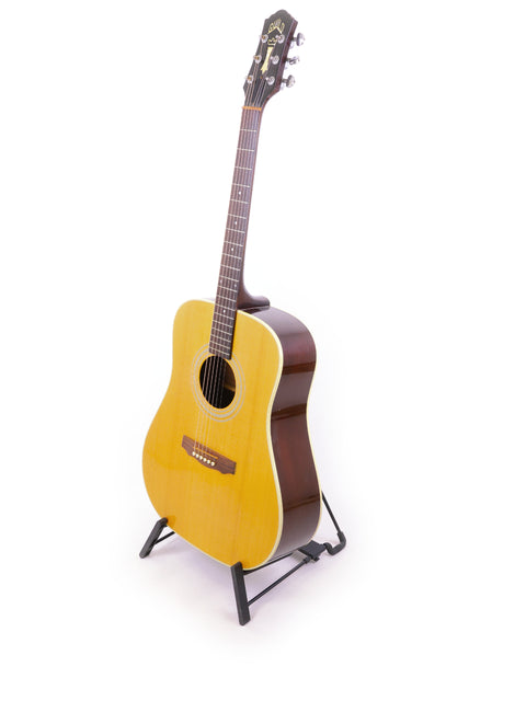 A 1989 Guild D40 guitar rests on a stand, showcasing its design against a stark white background.
