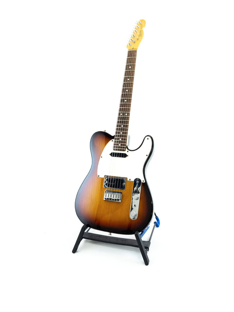 A 1991 Fender Telecaster Plus v.1 guitar displayed on a stand, featuring a striking design against a white backdrop.