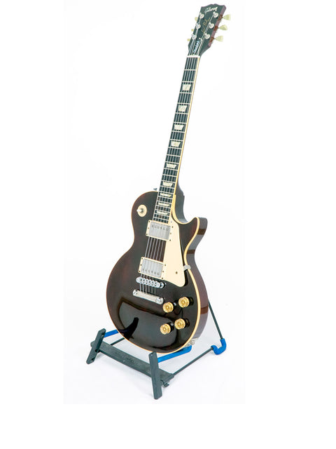 A 1991 Gibson Les Paul Standard guitar resting on a stand, set against a simple white backdrop.