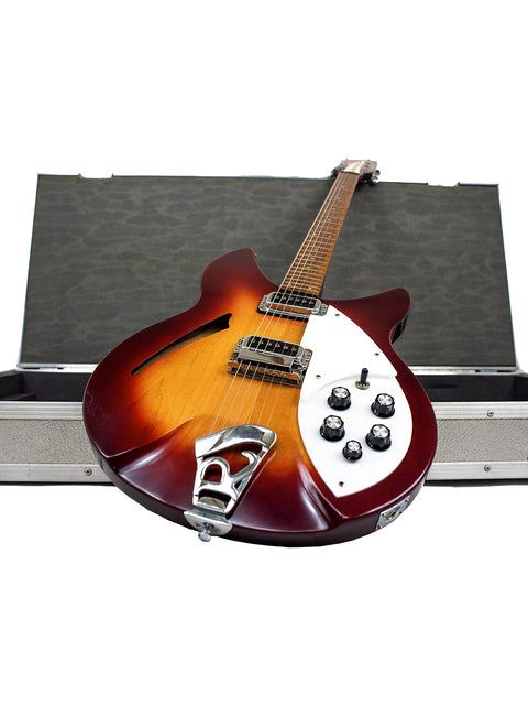 A 1994 Rickenbacker 330 guitar in a case, topped with another case, highlighting its vibrant Fireglo color.