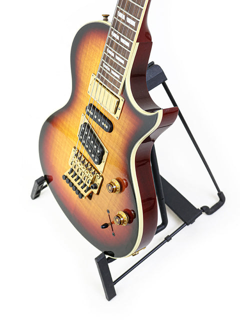 A 1997 Gibson Nighthawk guitar is displayed on a stand, set against a striking black backdrop, highlighting its craftsmanship.