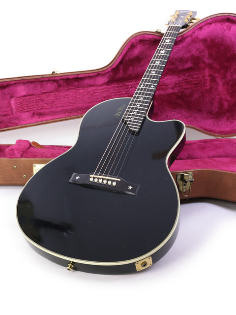 A 1998 black Gibson Chet Atkins SST guitar in its case, displayed on a bright white background.
