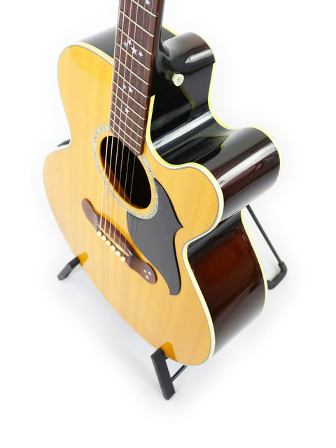 A 2001 Gibson J-180EC guitar resting on a stand, set against a simple white backdrop.