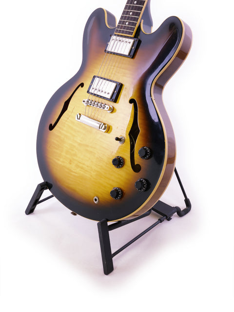  A 2006 Gibson ES-335 Nashville guitar displayed on a stand, featuring a striking white background for emphasis.