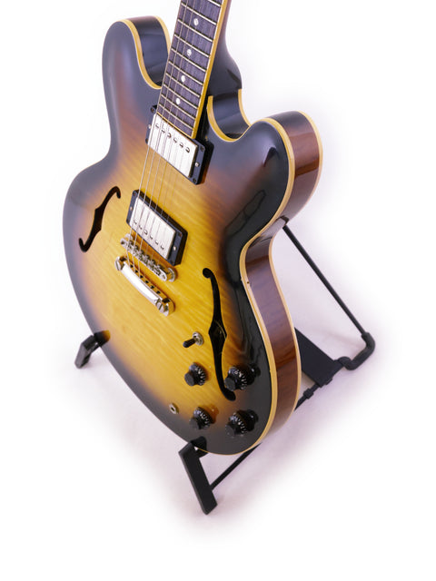 A 2006 Gibson ES-335 Nashville guitar elegantly positioned on a stand with a bright white backdrop.
