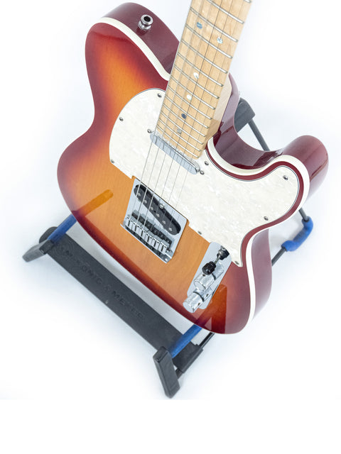 A 2007 Fender American Deluxe Telecaster guitar resting on a stand, featuring a stylish strap for easy playability.
