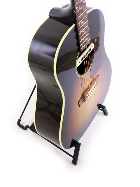 A 2012 Gibson J-45 True Vintage guitar displayed on a stand, featuring a striking white background for emphasis.