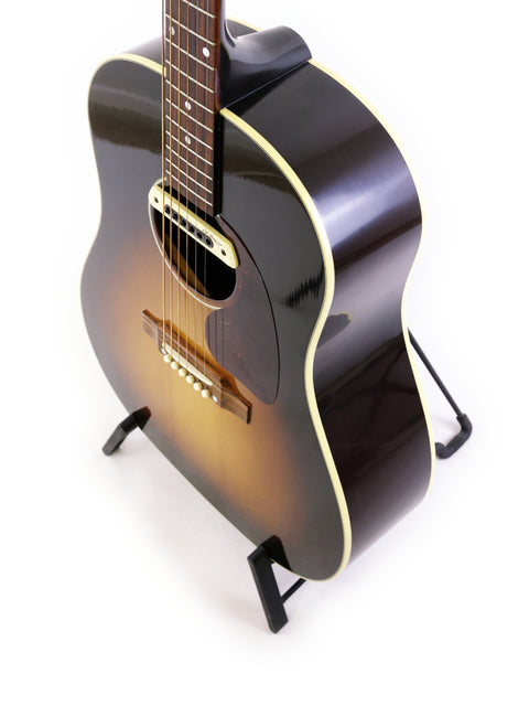 A 2012 Gibson J-45 True Vintage guitar elegantly displayed on a stand with a simple white backdrop.