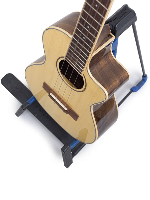 A 2019 Kala KA-SKT GE-C Tenor Uke with pickup displayed on a blue stand, highlighting its beautiful finish and features.