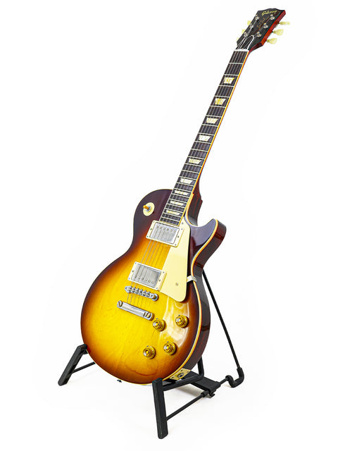 A 2020 Gibson Custom Shop 60th Anniversary 1960 Les Paul Standard guitar displayed on a stand with a white backdrop.
