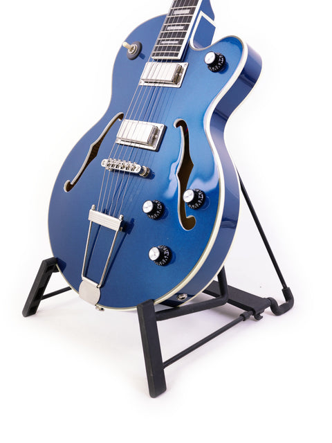 Blue Epiphone UpTown Kat ES guitar displayed on a stand with a bright white backdrop.