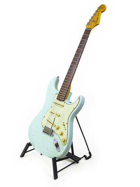 A Fender Custom Shop '59 Stratocaster electric guitar on a stand, showcasing its classic design and craftsmanship.