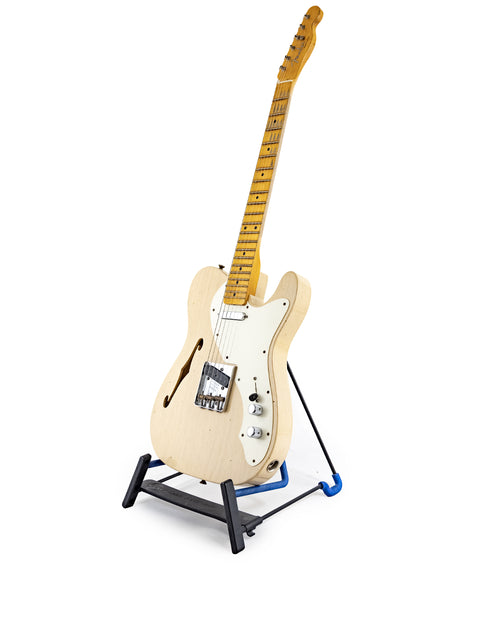 A Fender Custom Shop Limited Edition '50s Thinline Relic Telecaster electric guitar rests elegantly on a stand, highlighting its craftsmanship.