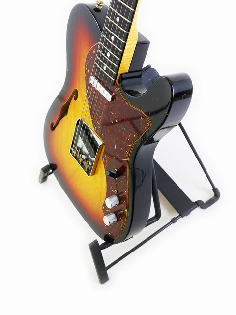 A Fender Limited Edition ’60s Telecaster Thinline Journeyman Relic guitar with a sunburst finish on a stand.