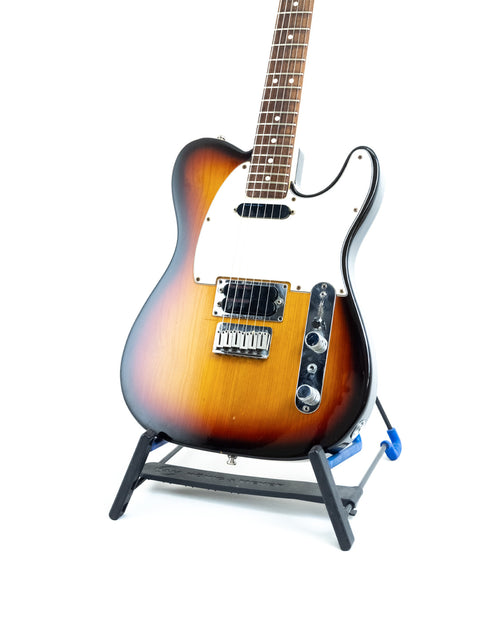 A Fender Telecaster Plus v.1 guitar elegantly positioned on a stand, with a minimalist white backdrop highlighting its features.
