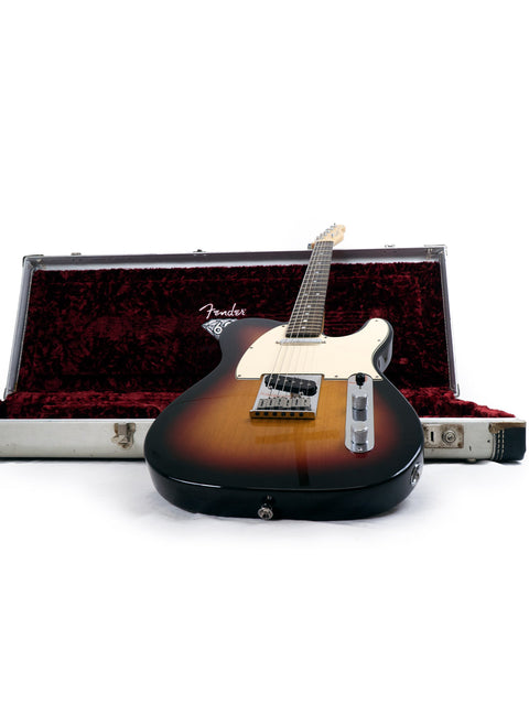 A Fender guitar in a sunburst finish resting on an open case with red velvet interior.
