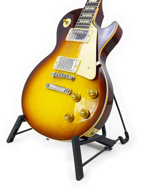  A Gibson Custom Shop 1960 Les Paul Standard guitar on a stand, featuring a white background for a sleek presentation.