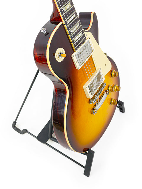 A Gibson Custom Shop 60th Anniversary 1960 Les Paul Standard guitar resting on a stand, showcasing its elegant design.