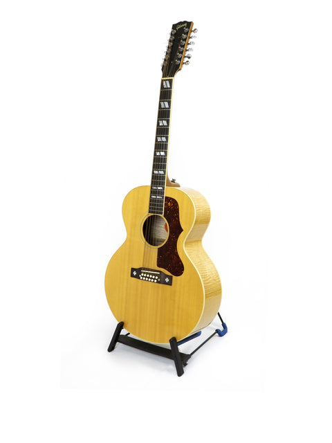 A Gibson J-185-12 string guitar displayed on a stand, featuring a sleek design against a bright white backdrop.