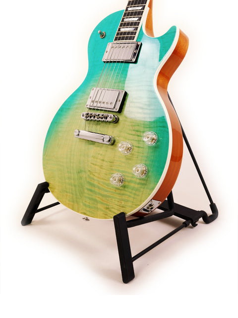 A Gibson Les Paul HP guitar displayed on a stand, with a striking green and blue backdrop.