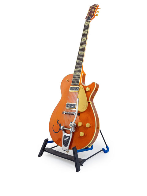 A Gretsch Roundup 6121W Reissue guitar displayed on a stand, set against a stark white background, highlighting its features.