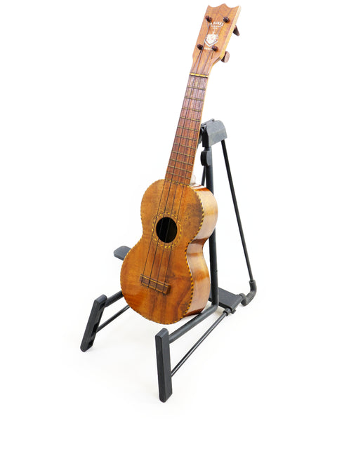 A Manuel Nunes Style #3 ukulele, crafted in 1917, sits proudly on a stand.