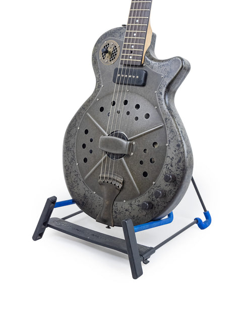 A National Reso-Phonic Polychrome Tricone Resonator guitar displayed on a blue stand, highlighting its artistic features.