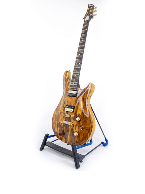 A PRS-style Ed Roman Quicksilver guitar with a wooden body resting on a stand, made in the USA in 2004.