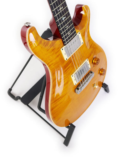A PRS Custom 22 guitar from 2005 displayed on a stand, set against a simple white backdrop for a striking visual.
